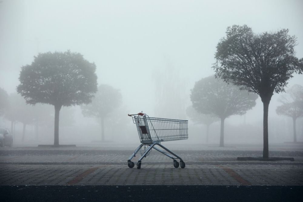 remarketing Carrinho de compras vazio abandonado em um estacionamento com neblina, simbolizando a necessidade de uma estratégia de remarketing.