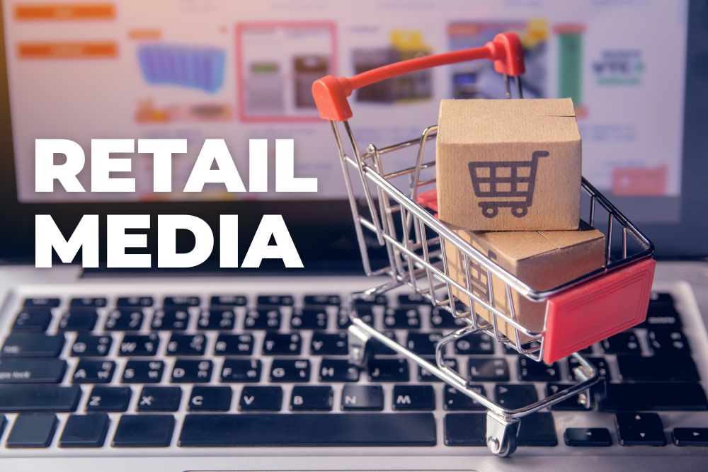 retail media no brasil Carrinho de compras em miniatura com caixas de papelão sobre um teclado de notebook, tendo ao fundo a tela de um e-commerce e o texto em destaque retail media no brasil, representando a publicidade digital no varejo.
