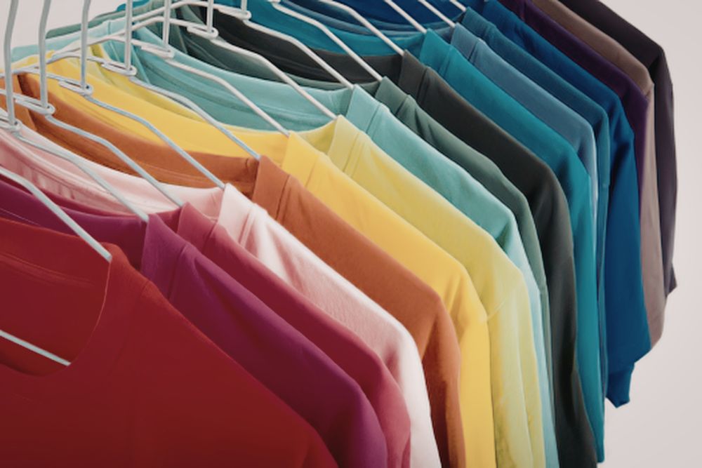 Taxa das blusinhas Araras com camisetas coloridas enfileiradas em cabides brancos, representando os produtos de vestuário importados afetados pelo fim da taxa das blusinhas no Brasil.